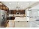 Modern kitchen boasts stainless steel appliances, dark cabinets, and a large island with quartz countertops at 12172 W Davis Ln, Avondale, AZ 85323