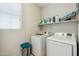 Functional laundry room with modern washer and dryer units and shelving at 12172 W Davis Ln, Avondale, AZ 85323
