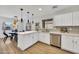 Bright kitchen features white cabinetry, quartz countertops, stainless appliances, and views to dining area at 12469 W Hearn Rd, El Mirage, AZ 85335