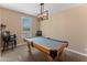 A game room with beige walls and carpet flooring featuring a billiards table under a modern chandelier at 13806 W Remuda Dr, Peoria, AZ 85383