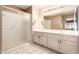Bathroom featuring dual sinks, spacious vanity, and shower with glass door at 14154 W Yosemite Dr, Sun City West, AZ 85375