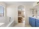 Bright bathroom featuring a separate tub and shower, blue vanity, and view into the bedroom at 1518 W Crape Rd, San Tan Valley, AZ 85140