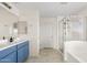 Bright bathroom with blue vanity, double sinks, and a glass-enclosed shower with a separate bathtub at 1518 W Crape Rd, San Tan Valley, AZ 85140