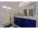 Bright bathroom features a double sink vanity with blue cabinets and a large shower at 15246 N 138Th Ln, Surprise, AZ 85379