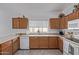 Bright kitchen with a stainless steel sink, wood cabinets, and white appliances at 15246 N 138Th Ln, Surprise, AZ 85379