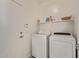 Functional laundry room with modern washer and dryer and built-in storage shelves at 15246 N 138Th Ln, Surprise, AZ 85379