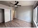 Bright bedroom features wood-look floors, a ceiling fan, closet, and a window with a view of the outside at 1704 E Redfield Rd, Gilbert, AZ 85234