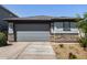 Charming home featuring a grey garage door, stone accents, and low-maintenance landscaping at 17320 W Daley Ln, Surprise, AZ 85387