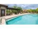 Inviting pool area with shaded pergola, dining tables, sun loungers, and meticulously kept landscaping at 18550 N 94Th St, Scottsdale, AZ 85255