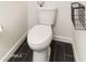 Close-up of a modern toilet with dark wood-look tile flooring and minimalist design at 18550 N 94Th St, Scottsdale, AZ 85255
