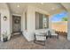 Inviting covered porch with comfortable seating, a stylish front door with wreath, and brick-paved flooring at 1876 S Huish Dr, Gilbert, AZ 85295
