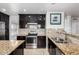 Modern kitchen featuring stainless steel appliances, granite countertops, dark cabinets, and tiled backsplash at 20410 N 51St Dr, Glendale, AZ 85308