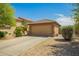 Beige two-car garage with desert landscaping, tile roof, and a spacious driveway at 22191 W Tonto St, Buckeye, AZ 85326