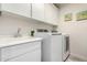 Bright laundry room with sink, modern washer and dryer, white cabinets, and neutral paint at 2533 W Cordia Ln, Phoenix, AZ 85085