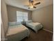 This bedroom features two twin beds, a ceiling fan and a window with blinds at 30395 W Mitchell Ave, Buckeye, AZ 85396
