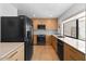 Well-lit kitchen with wooden cabinets, granite countertops, black appliances and tile backsplash, offering modern convenience at 309 E Huntington Dr, Tempe, AZ 85282