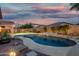 Serene backyard pool area illuminated at dusk, featuring a rock waterfall, desert landscaping and outdoor seating at 4089 E Peach Tree Dr, Chandler, AZ 85249