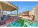 Relaxing backyard features covered patio, lounge seating, outdoor kitchen, playset, and manicured green lawn at 4138 N 298Th Ln, Buckeye, AZ 85396