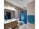 Neutral bathroom featuring a tub with a blue shower curtain, toilet, vanity, and large mirror at 4138 N 298Th Ln, Buckeye, AZ 85396