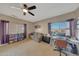 Bright bedroom with a ceiling fan, desk, sofa, and plenty of natural light from the window at 4138 N 298Th Ln, Buckeye, AZ 85396