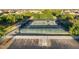 A tennis court is surrounded by tall green trees and a parking lot in the foreground at 44355 W Oster Dr, Maricopa, AZ 85138