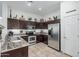 A well-lit kitchen featuring stainless steel appliances, dark cabinets, tile backsplash, and decorative tile countertops at 582 W Stirrup Ln, San Tan Valley, AZ 85143