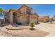 Front exterior view of a two-story home with a well-manicured desert landscape and a three-car garage at 5953 W Aurora Dr, Glendale, AZ 85308