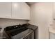 Modern laundry room includes front loading washer, dryer, and upper cabinets at 5953 W Aurora Dr, Glendale, AZ 85308