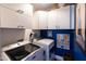 An organized laundry room is equipped with white cabinets, contemporary machines, and blue accent wall at 6314 N 14Th St, Phoenix, AZ 85014