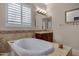 This bathroom features a soaking tub, tile floors, warm neutral paint, and plantation shutters at 6694 S Banning St, Gilbert, AZ 85298