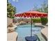 Backyard pool area featuring rock waterfall, basketball hoop, and red umbrella at 720 W Gail Ct, Gilbert, AZ 85233