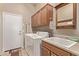Bright laundry room with tile floor, utility sink, cabinets, and appliances at 766 E Taylor Trl, San Tan Valley, AZ 85143