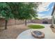 Expansive backyard featuring gravel, a stone-lined path, mature shade trees, and a built-in fire pit at 81 E Rock Wren Dr, San Tan Valley, AZ 85143