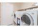 Bright laundry room with front-loading washer, dryer, upper shelving, and white door at 81 E Rock Wren Dr, San Tan Valley, AZ 85143