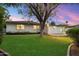 Manicured backyard with green lawn, covered patio, and mature trees at 8228 E Oak St, Scottsdale, AZ 85257