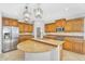 Well-lit kitchen with wooden cabinets, granite countertop island, modern appliances, and stylish pendant lighting at 880 E Wimpole Ave, Gilbert, AZ 85297