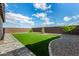 Lush backyard features well-maintained artificial turf, landscaping, and clear blue skies creating inviting outdoor space at 19875 W Badgett Ln, Litchfield Park, AZ 85340