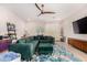 Spacious living room featuring modern decor, a ceiling fan, and an inviting emerald green sectional at 19875 W Badgett Ln, Litchfield Park, AZ 85340