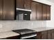 Up close detail of the modern kitchen featuring granite countertops, dark cabinets, and a stainless steel range at 37111 W Parador Ln, Maricopa, AZ 85138