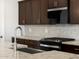 Up close detail of the modern kitchen featuring granite countertops, dark cabinets, and a stainless steel range at 37111 W Parador Ln, Maricopa, AZ 85138
