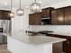Modern kitchen features granite countertops, dark cabinets, stainless steel appliances, and pendant lighting at 37111 W Parador Ln, Maricopa, AZ 85138