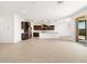 Bright, open-concept living space with tile floors and a view into the modern kitchen and access to the backyard at 37111 W Parador Ln, Maricopa, AZ 85138