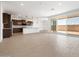 Bright, open-concept living space with tile floors and a view into the modern kitchen and outdoor patio at 37111 W Parador Ln, Maricopa, AZ 85138