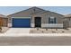 Charming single-story house boasts a blue garage door and desert-style front yard landscaping at 37151 W Parador Ln, Maricopa, AZ 85138