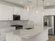 Close up of kitchen island with stainless steel appliances, granite countertops, and modern lighting fixtures at 37151 W Parador Ln, Maricopa, AZ 85138