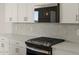 Close up of a kitchen stove with a stainless microwave and a light gray backsplash at 37151 W Parador Ln, Maricopa, AZ 85138