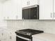 Modern kitchen showcasing stainless steel microwave and range with white cabinetry and backsplash at 4032 S 176Th Dr, Goodyear, AZ 85338