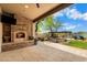 An outdoor covered patio has a stone fireplace, television, and built in grill at 5744 E Hedgehog Pl, Scottsdale, AZ 85266