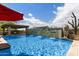 The stunning swimming pool has a rock waterfall and an adjacent outdoor kitchen and dining area at 5744 E Hedgehog Pl, Scottsdale, AZ 85266