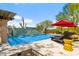 A private swimming pool with waterfall feature and comfortable lounge chairs under red umbrellas at 5744 E Hedgehog Pl, Scottsdale, AZ 85266